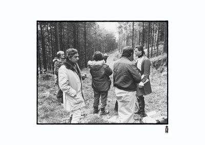 Stanley looks through his lens mounted, while Ken paces in the foreground - norrie maclaren